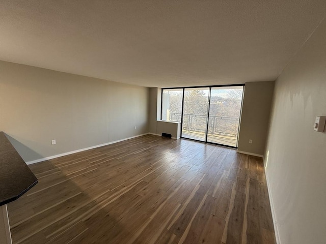 spare room with dark hardwood / wood-style floors and a wall of windows