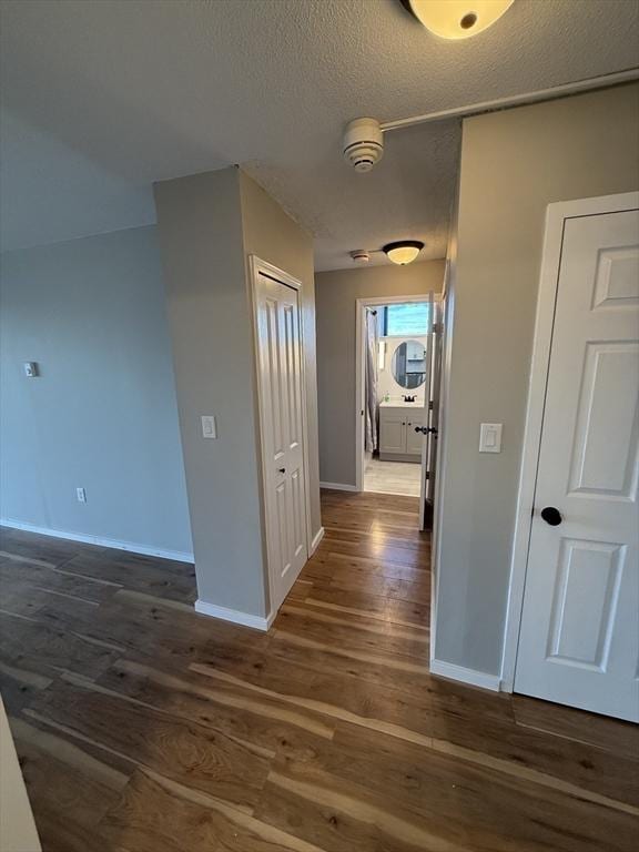 corridor with a textured ceiling and dark hardwood / wood-style floors