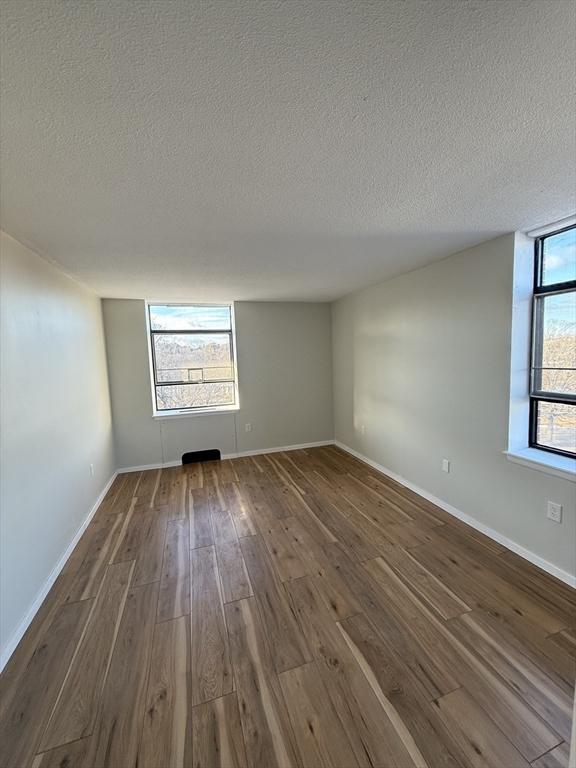 empty room with a textured ceiling and hardwood / wood-style flooring