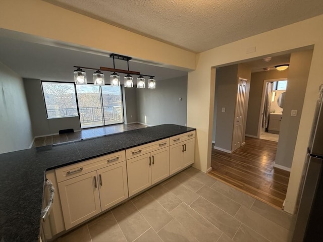 kitchen featuring light tile patterned floors, white cabinetry, a textured ceiling, and hanging light fixtures