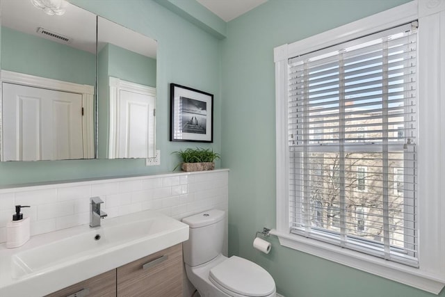 bathroom featuring tasteful backsplash, vanity, toilet, and a wealth of natural light