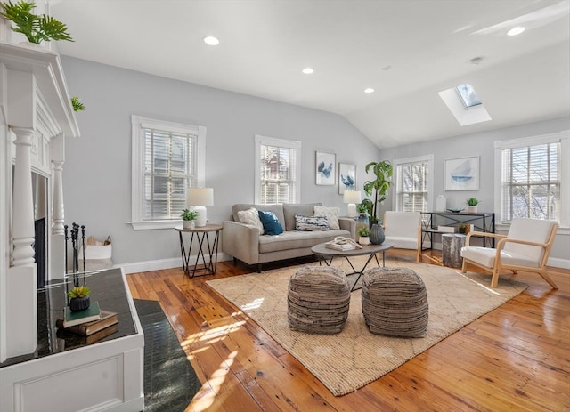 living room with vaulted ceiling with skylight and light hardwood / wood-style flooring