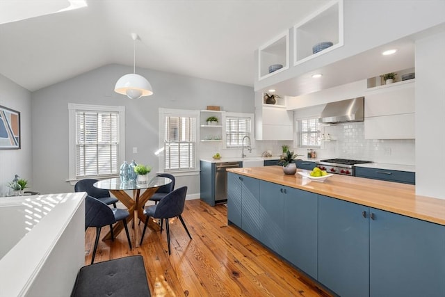 kitchen with hanging light fixtures, blue cabinets, white cabinets, and wall chimney exhaust hood