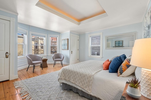 bedroom featuring hardwood / wood-style flooring, a tray ceiling, and crown molding