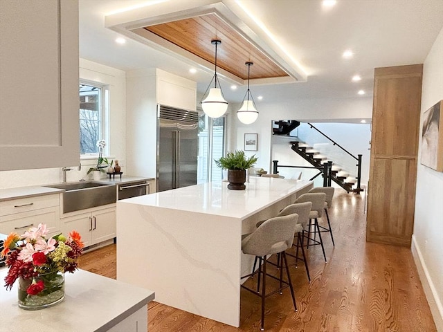 kitchen featuring built in fridge, a kitchen island, white cabinets, and pendant lighting