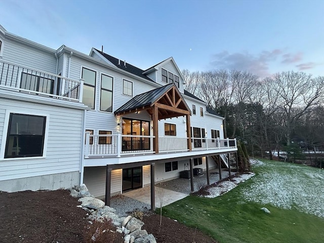 back of property with a patio, a balcony, and a lawn