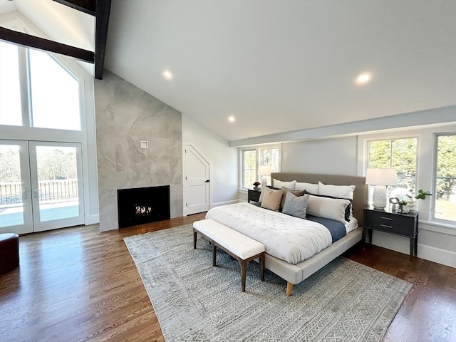 bedroom with wood-type flooring, lofted ceiling with beams, and multiple windows