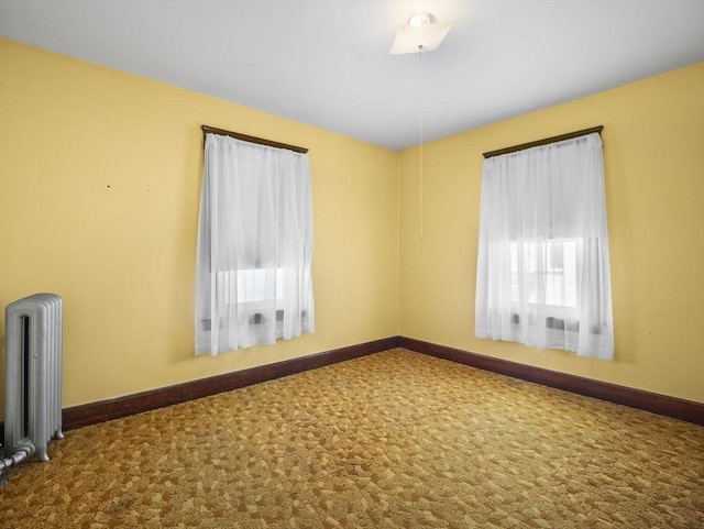 unfurnished room featuring carpet floors and radiator heating unit