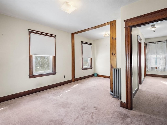 carpeted spare room featuring a healthy amount of sunlight and radiator heating unit