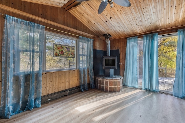 unfurnished living room featuring wood ceiling, a wood stove, vaulted ceiling with beams, and hardwood / wood-style floors