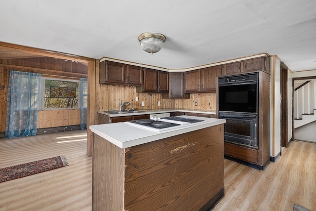 kitchen featuring white appliances, sink, a center island, dark brown cabinetry, and light hardwood / wood-style floors