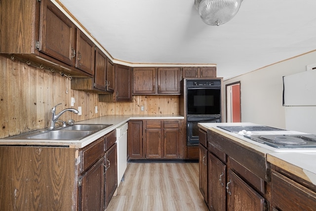 kitchen featuring dark brown cabinetry, sink, light wood-type flooring, and white appliances