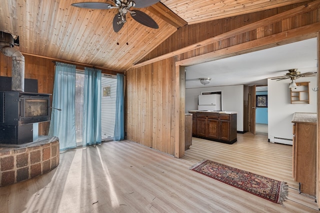 living room with a baseboard heating unit, light wood-type flooring, lofted ceiling with beams, a wood stove, and wooden walls