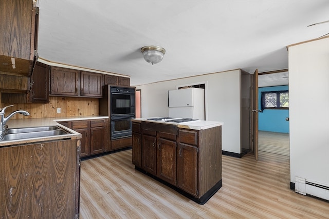 kitchen with light hardwood / wood-style floors, dark brown cabinets, sink, and a center island