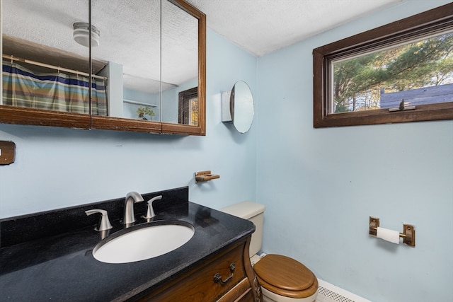 bathroom with vanity, toilet, a textured ceiling, and baseboard heating