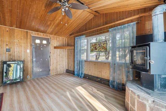 unfurnished living room with vaulted ceiling, wood ceiling, light wood-type flooring, and a wood stove