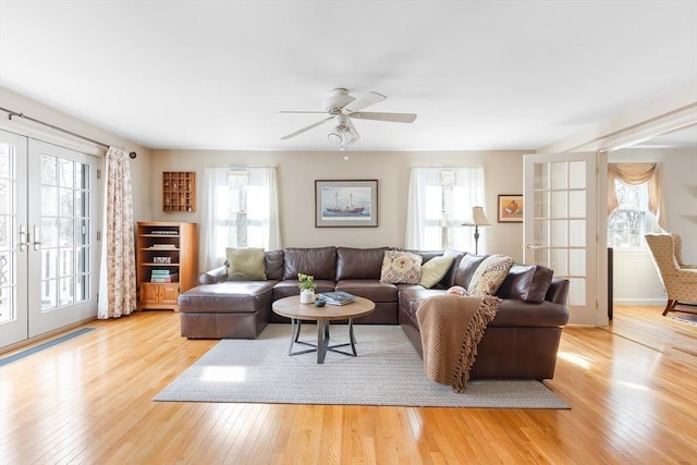 living area with a healthy amount of sunlight, wood-type flooring, and french doors