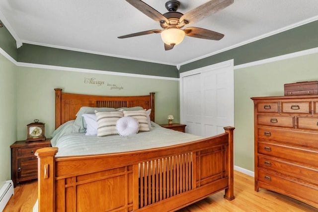 bedroom with a baseboard heating unit, crown molding, a closet, and light wood-type flooring