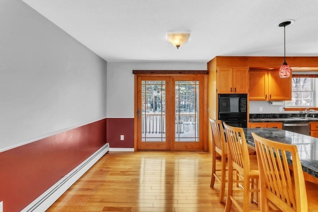 kitchen featuring light hardwood / wood-style flooring, dishwasher, black microwave, decorative light fixtures, and a baseboard radiator