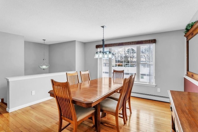 dining room with a baseboard heating unit, a textured ceiling, and light wood-type flooring