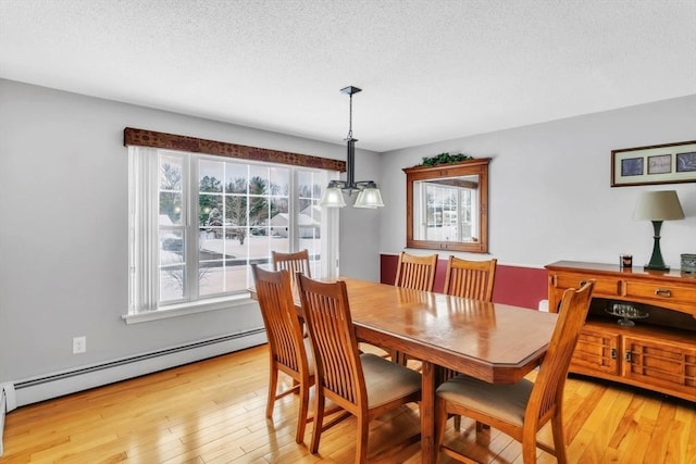 dining space featuring an inviting chandelier, a baseboard radiator, light hardwood / wood-style flooring, and a textured ceiling