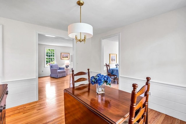 169 Mountainview Rd, East Longmeadow, MA 01028 - dining area with light wood-type flooring, a wainscoted wall, and a chandelier