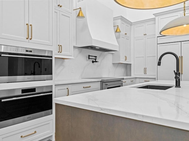 kitchen with white cabinetry, sink, custom exhaust hood, light stone counters, and stainless steel appliances