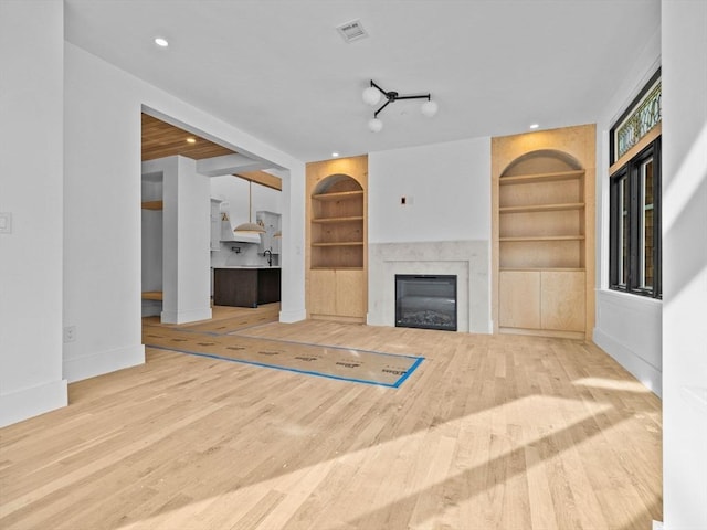 unfurnished living room featuring wood-type flooring and built in features