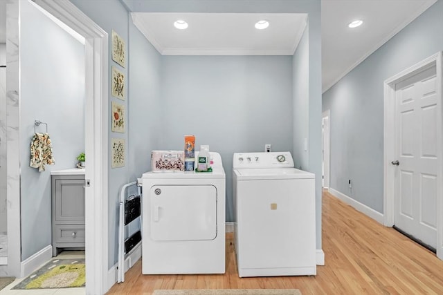 laundry room with ornamental molding, washer and clothes dryer, and light hardwood / wood-style floors