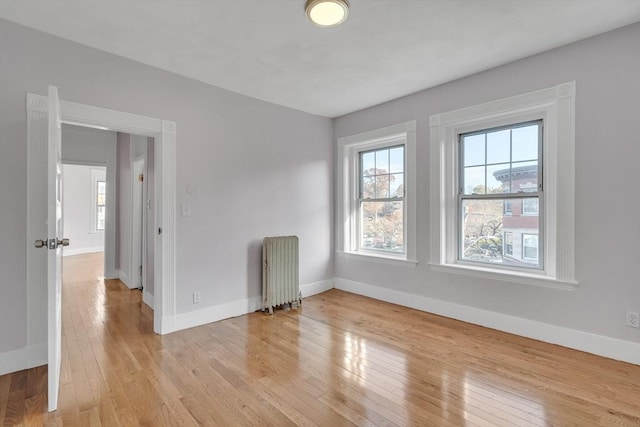 unfurnished room with radiator heating unit, light hardwood / wood-style floors, and plenty of natural light