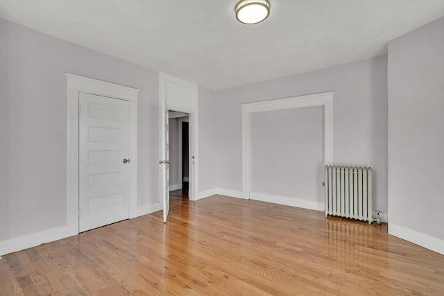 unfurnished room featuring radiator and light wood-type flooring