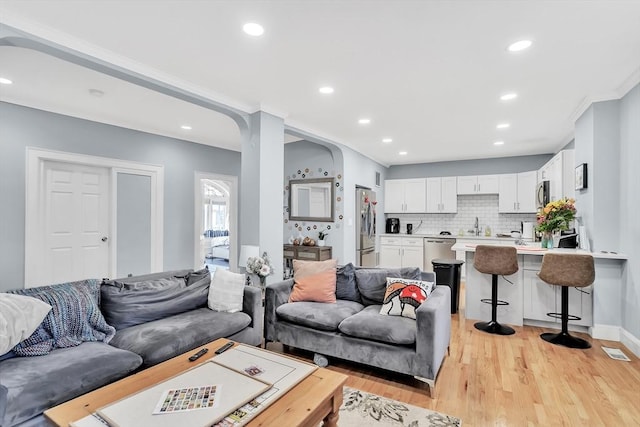 living room featuring sink, light hardwood / wood-style flooring, and ornamental molding