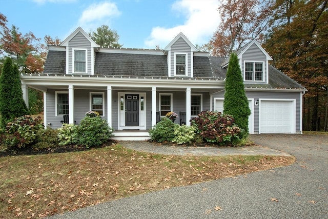 view of front of home with an attached garage, aphalt driveway, a porch, and a shingled roof