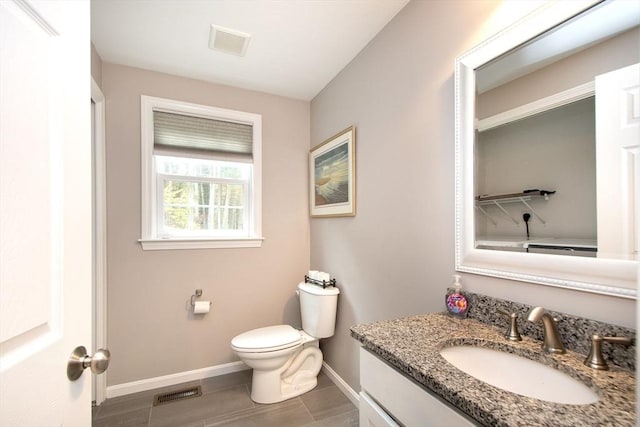 bathroom featuring toilet, vanity, visible vents, and baseboards