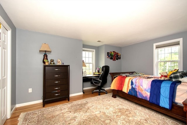 bedroom featuring visible vents, baseboards, and wood finished floors