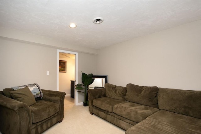 living area featuring baseboards, visible vents, and light colored carpet