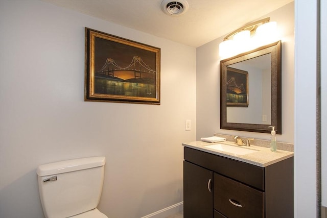 bathroom with toilet, vanity, visible vents, and baseboards