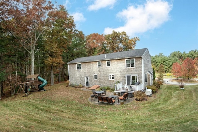 back of property with a wooden deck, a playground, and a yard