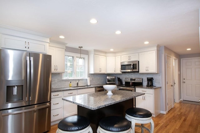 kitchen featuring appliances with stainless steel finishes, a breakfast bar area, a sink, and decorative backsplash