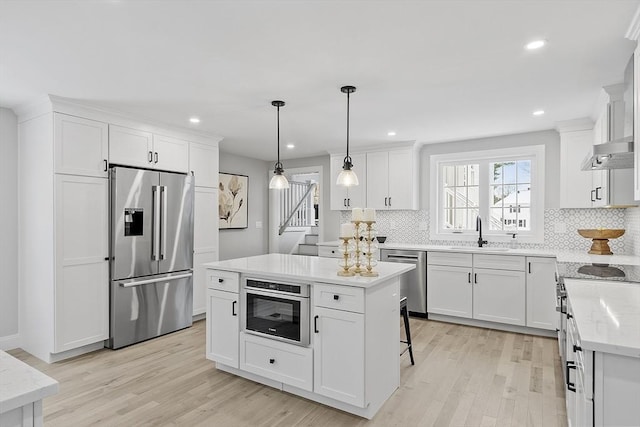 kitchen with sink, decorative light fixtures, a kitchen island, white cabinetry, and stainless steel appliances