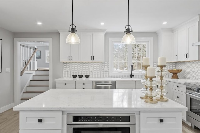 kitchen with light stone countertops, sink, white cabinetry, and hanging light fixtures