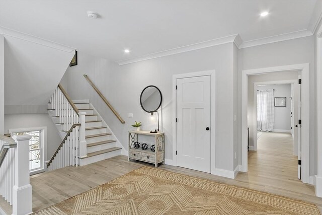 entrance foyer featuring crown molding and light hardwood / wood-style floors