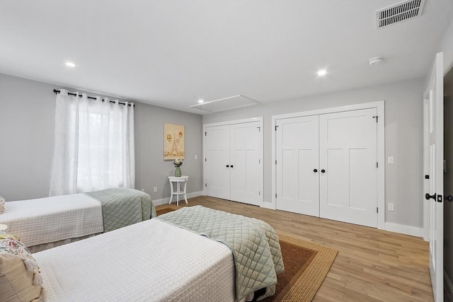 bedroom with light wood-type flooring and two closets