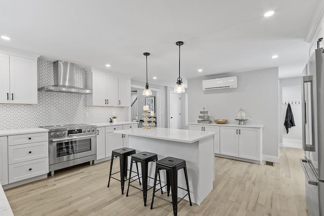 kitchen featuring white cabinets, premium appliances, a wall mounted AC, and wall chimney exhaust hood