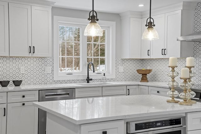 kitchen featuring light stone countertops, sink, backsplash, decorative light fixtures, and white cabinets