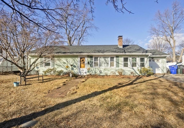 back of property featuring a garage and a lawn