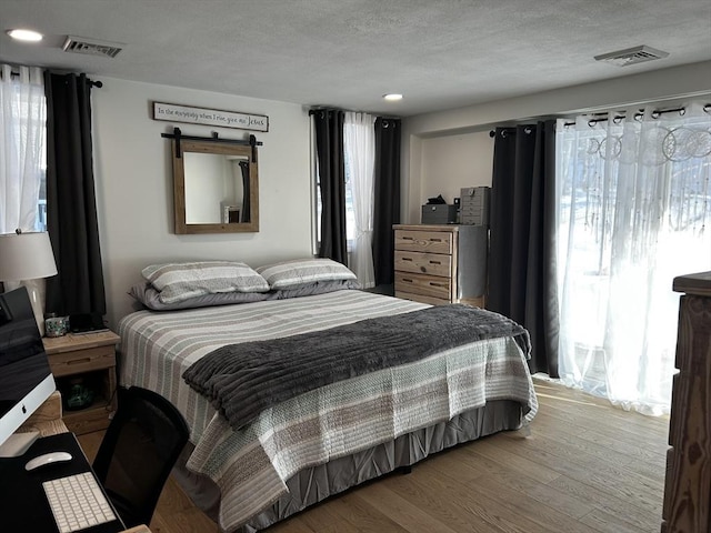 bedroom featuring multiple windows, wood finished floors, and visible vents