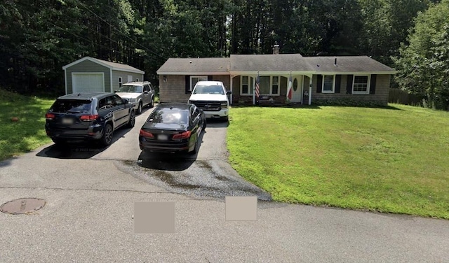 ranch-style home with driveway, a detached garage, an outbuilding, and a front yard