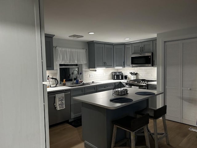 kitchen featuring gray cabinets, stainless steel microwave, stove, a sink, and dishwashing machine