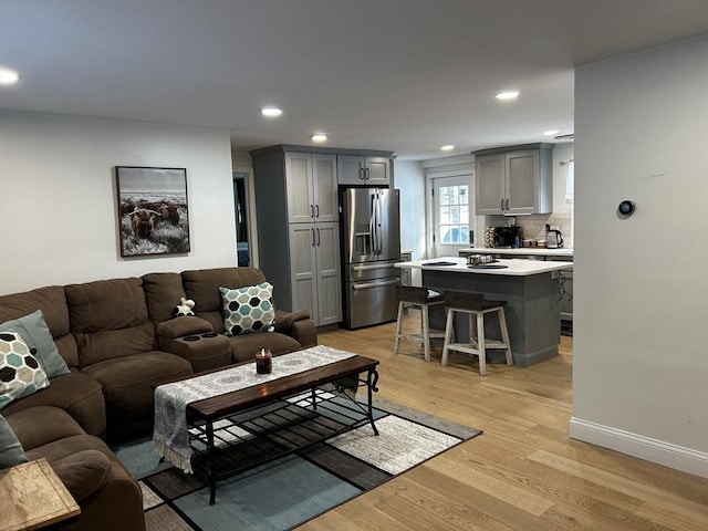 living room featuring light wood-type flooring, baseboards, and recessed lighting